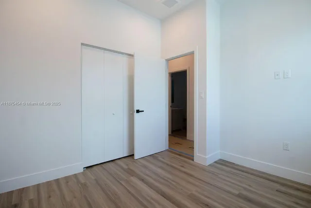 a view of an empty room with wooden floor and closet