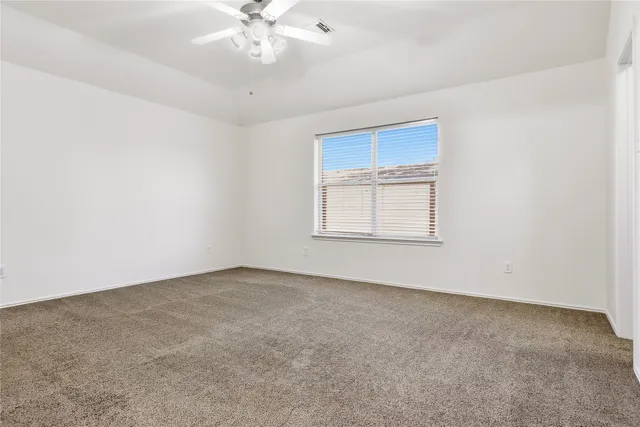 an empty room with a chandelier fan and windows