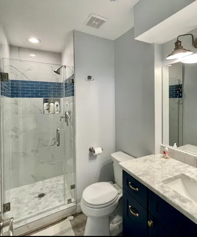 a bathroom with a granite countertop sink a toilet and shower