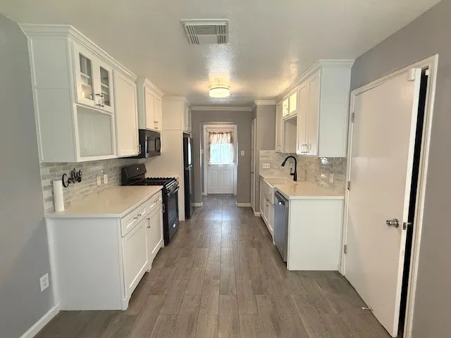 a kitchen with sink a refrigerator and wooden floor
