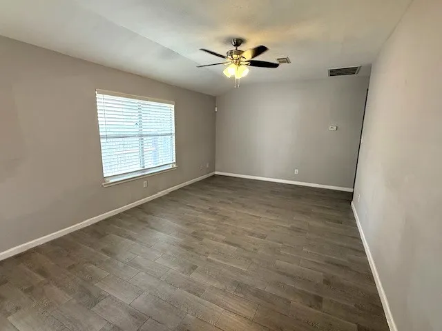 an empty room with windows and fan