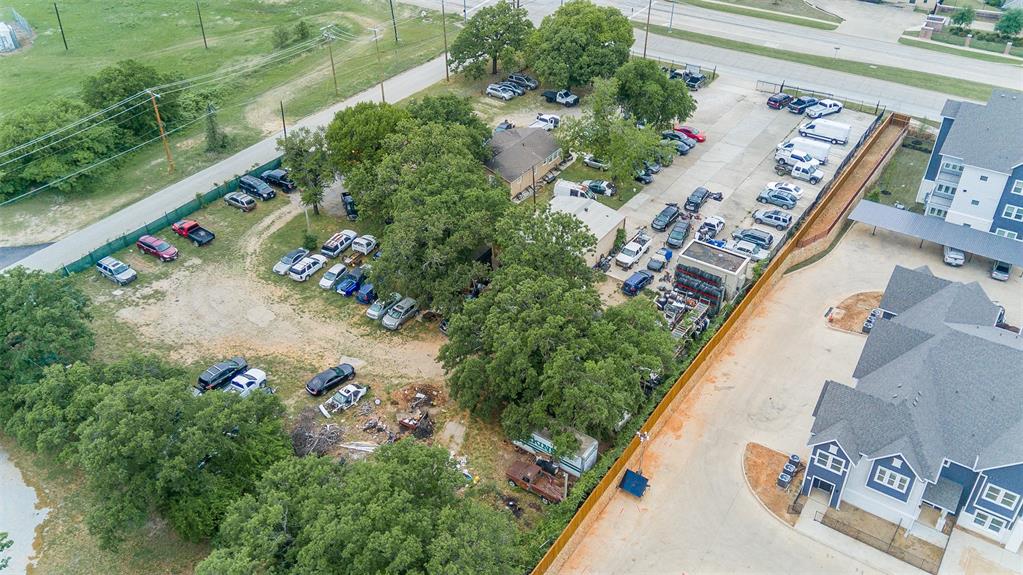 3410 House Anderson Road Euless, TX 76040 - Photo 13 of 18 Expansive commercial property featuring a paved parking area, a central building, perimeter fencing, and mature trees