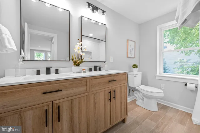 a bathroom with a double vanity sink mirror and toilet