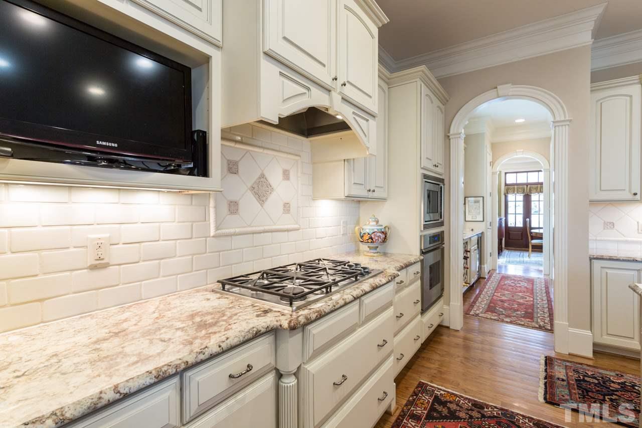 2308 Beechridge Road Raleigh, NC 27608 - Photo 11 of 27 a kitchen with stainless steel appliances kitchen island granite countertop a stove and a wooden floor