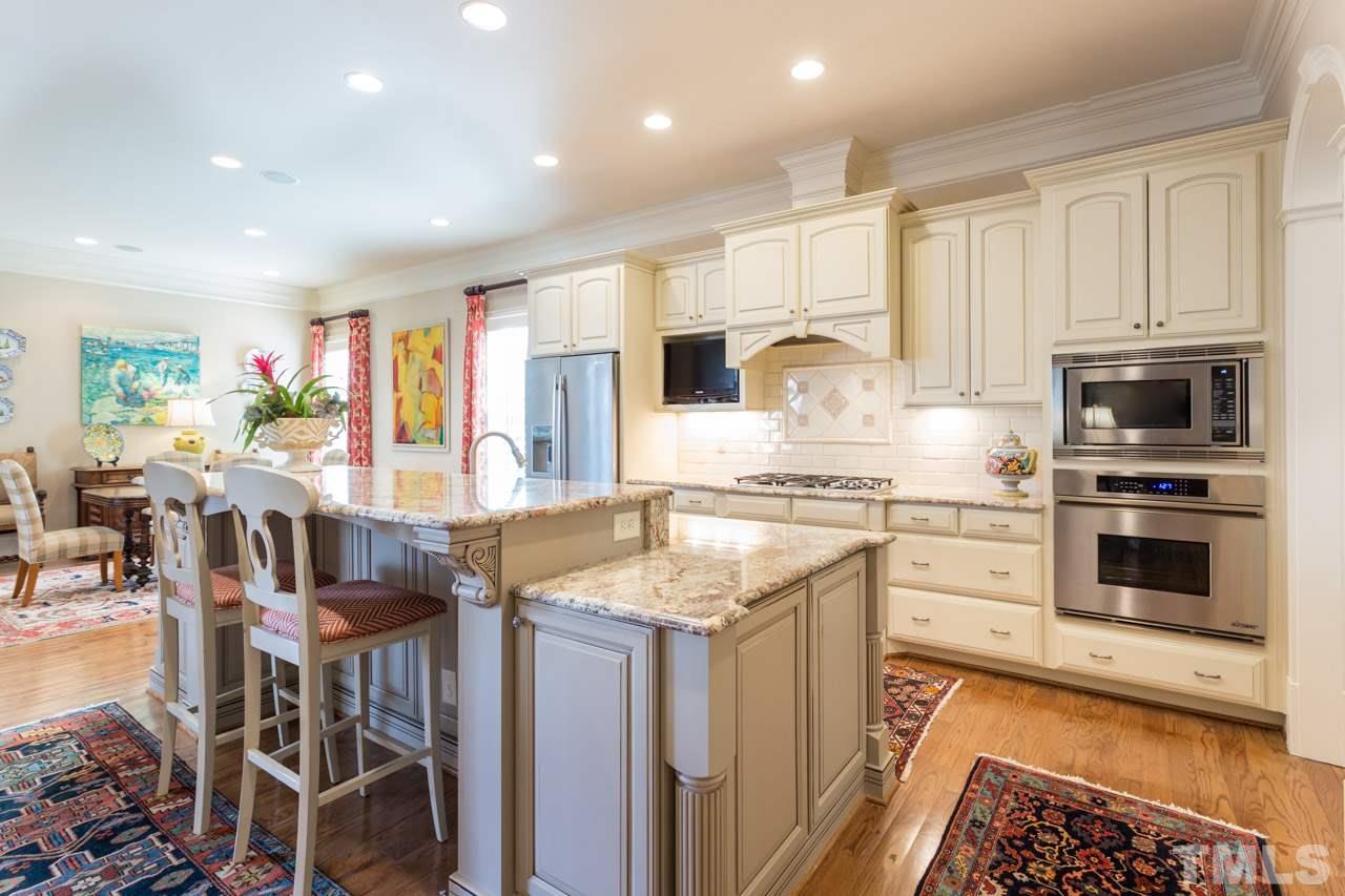 2308 Beechridge Road Raleigh, NC 27608 - Photo 12 of 27 a kitchen with stainless steel appliances granite countertop a stove top oven a sink a dining table and chairs with wooden floor