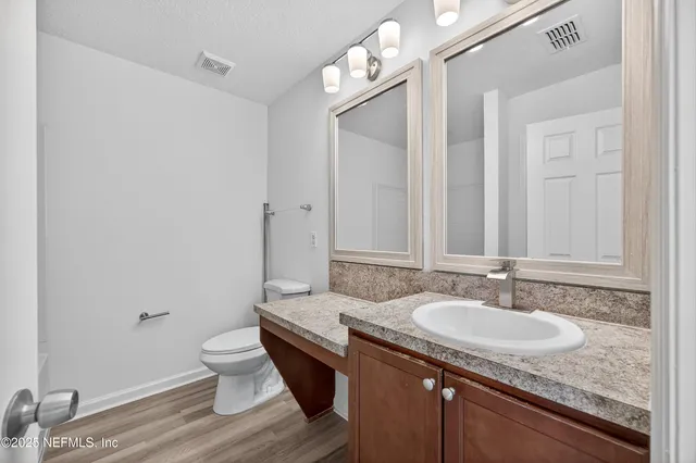 a bathroom with a granite countertop sink a toilet and a mirror