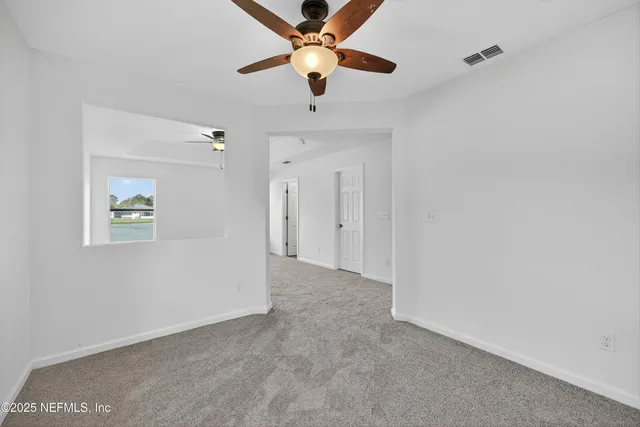 an empty room with a window and a ceiling fan
