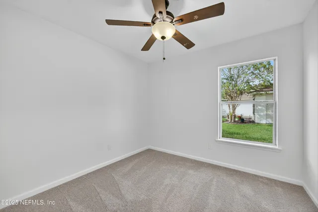 an empty room with a window and a fan