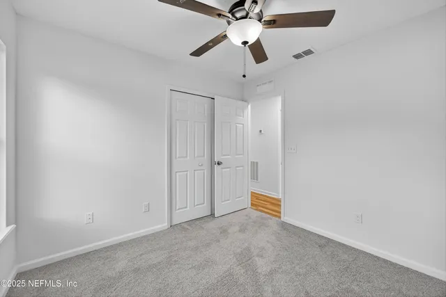 en empty room with ceiling fan and window