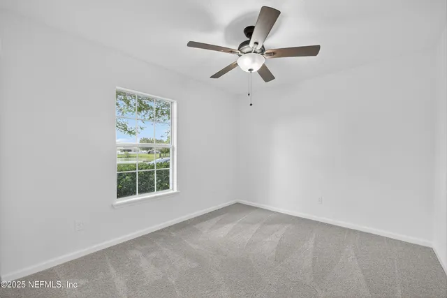 an empty room with a window and a fan