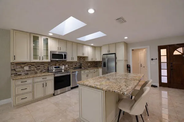 a kitchen with stainless steel appliances granite countertop a stove refrigerator sink and cabinets