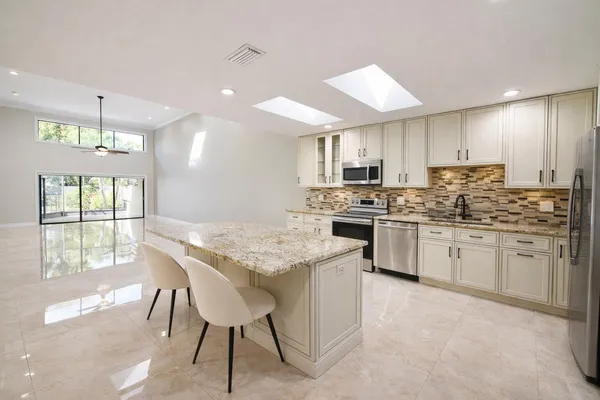 a kitchen with stainless steel appliances kitchen island granite countertop a stove a sink and a refrigerator