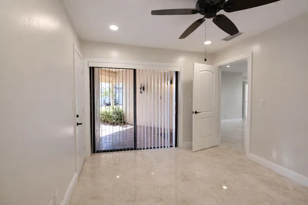 an empty room with ceiling fan and windows
