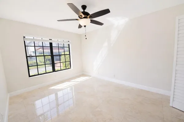 an empty room with windows and ceiling fan view