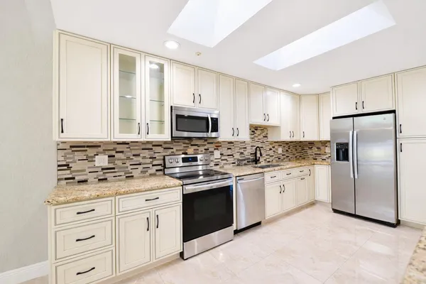 a kitchen with granite countertop white cabinets white stainless steel appliances with a sink and dishwasher