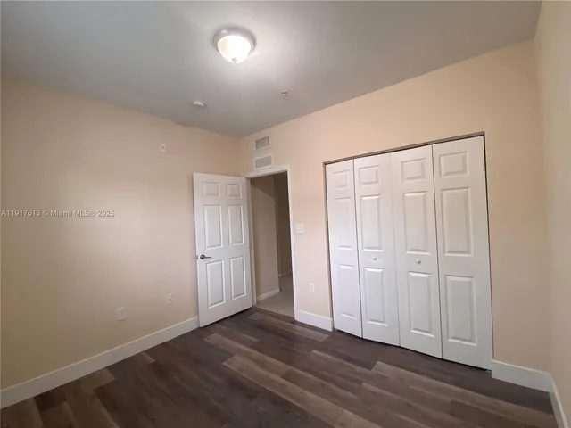 an empty room with wooden floor and closet area