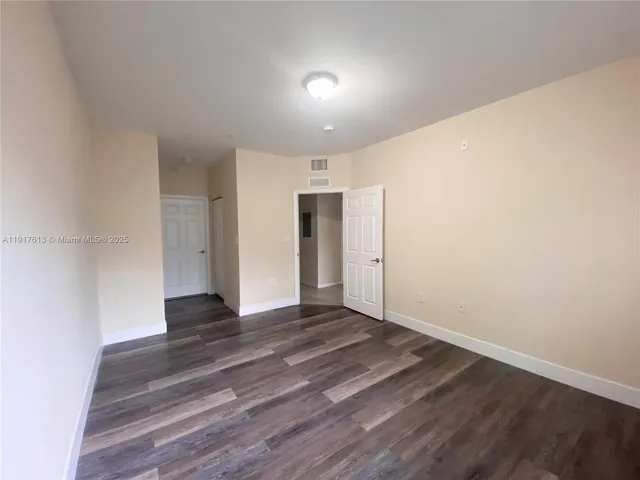 a view of an empty room with wooden floor and closet