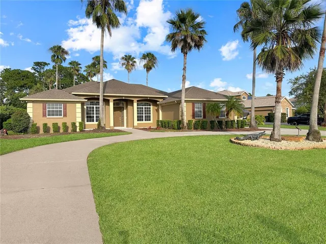 a front view of a house with a garden and palm trees