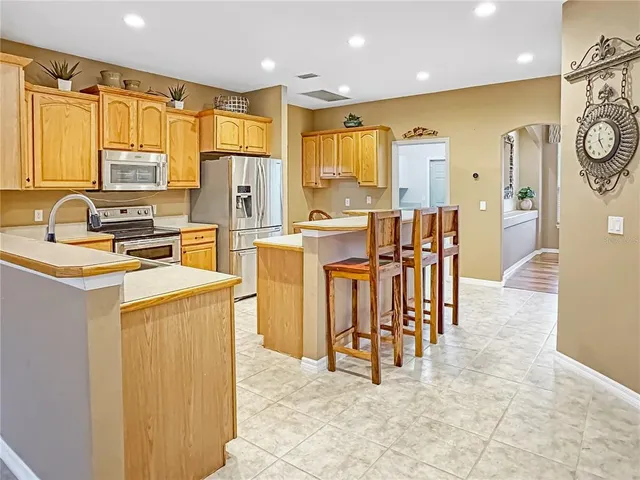 a view of kitchen with stainless steel appliances refrigerator stove microwave and cabinets