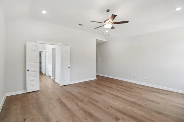 a view of an empty room with a window and wooden floor
