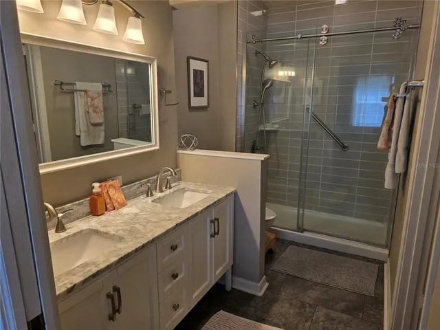 a bathroom with a granite countertop sink a mirror and shower