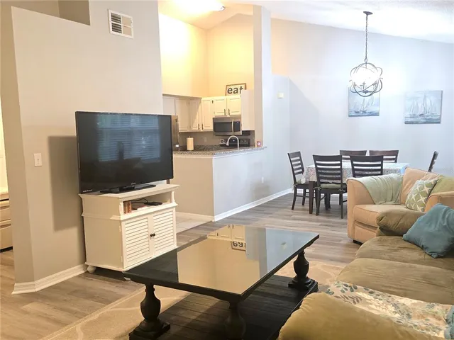 a living room with furniture kitchen view and a flat screen tv