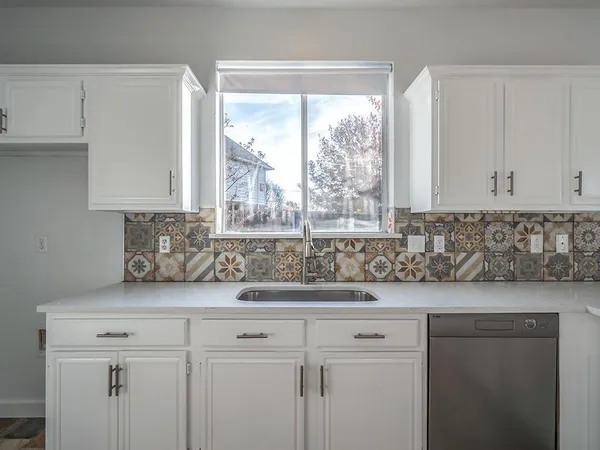 a sink with white cabinets and a window