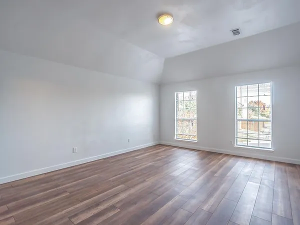 a view of a big room with wooden floor and windows