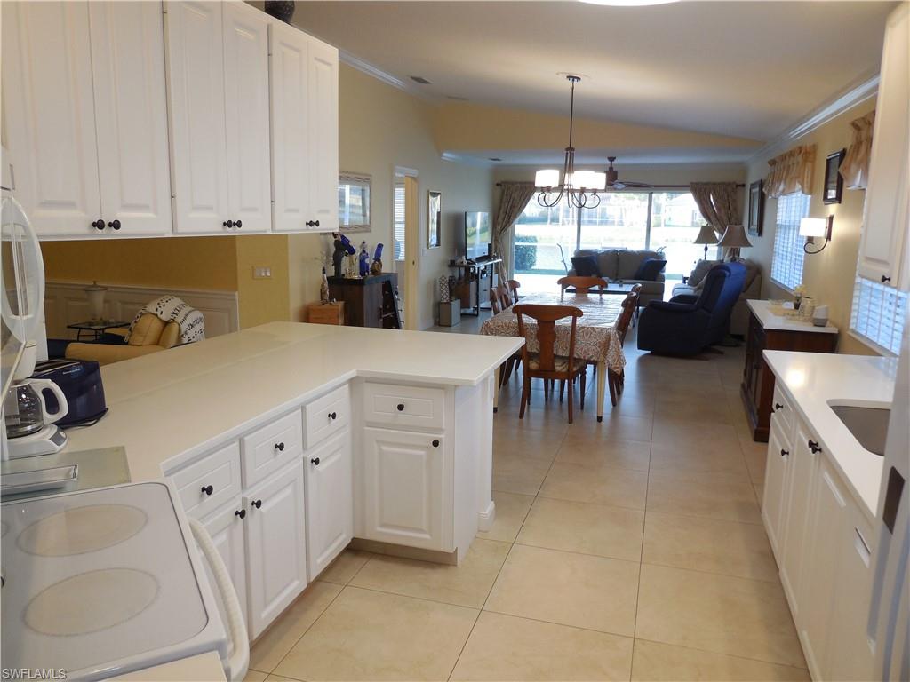 3703 Exuma Way Naples, FL 34119 - Photo 6 of 47 a kitchen with granite countertop a sink a counter top space appliances and cabinets