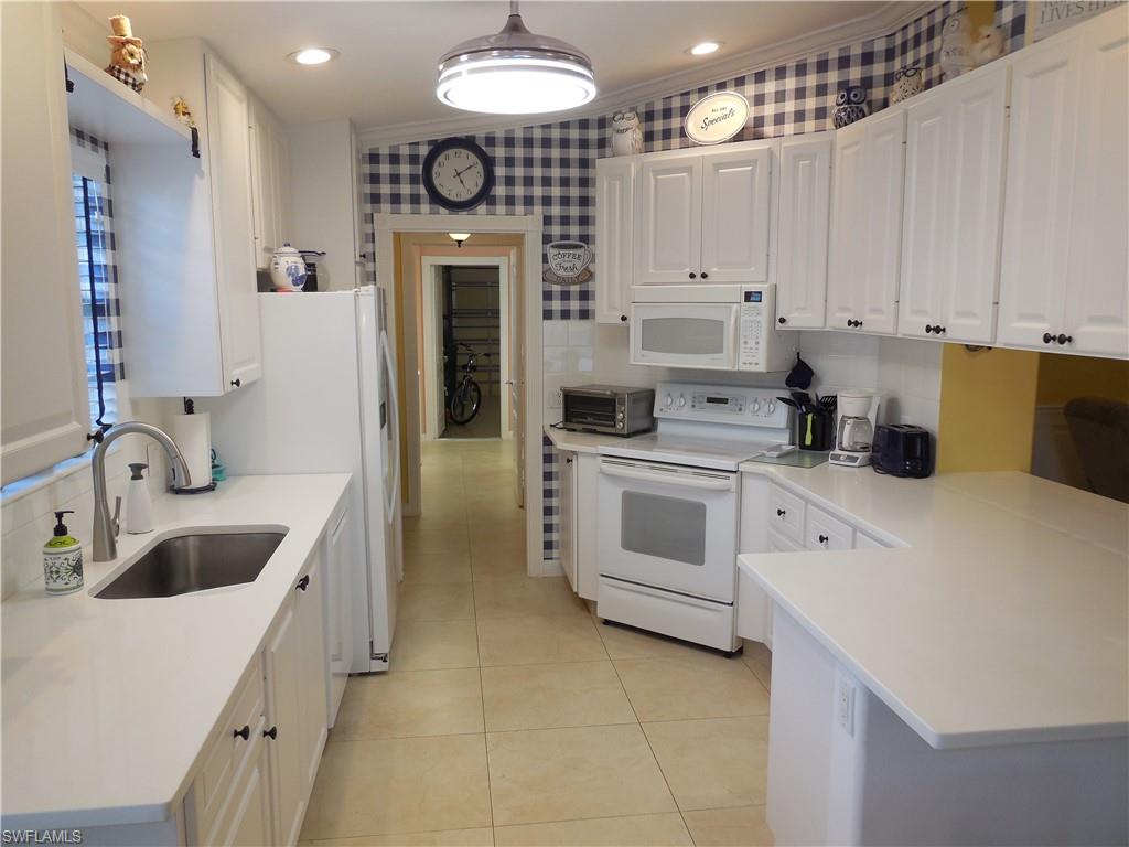 3703 Exuma Way Naples, FL 34119 - Photo 7 of 47 a kitchen with white cabinets and white appliances
