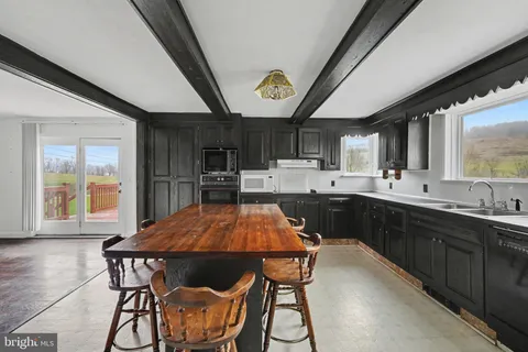 a kitchen with stainless steel appliances a table chairs sink and cabinets