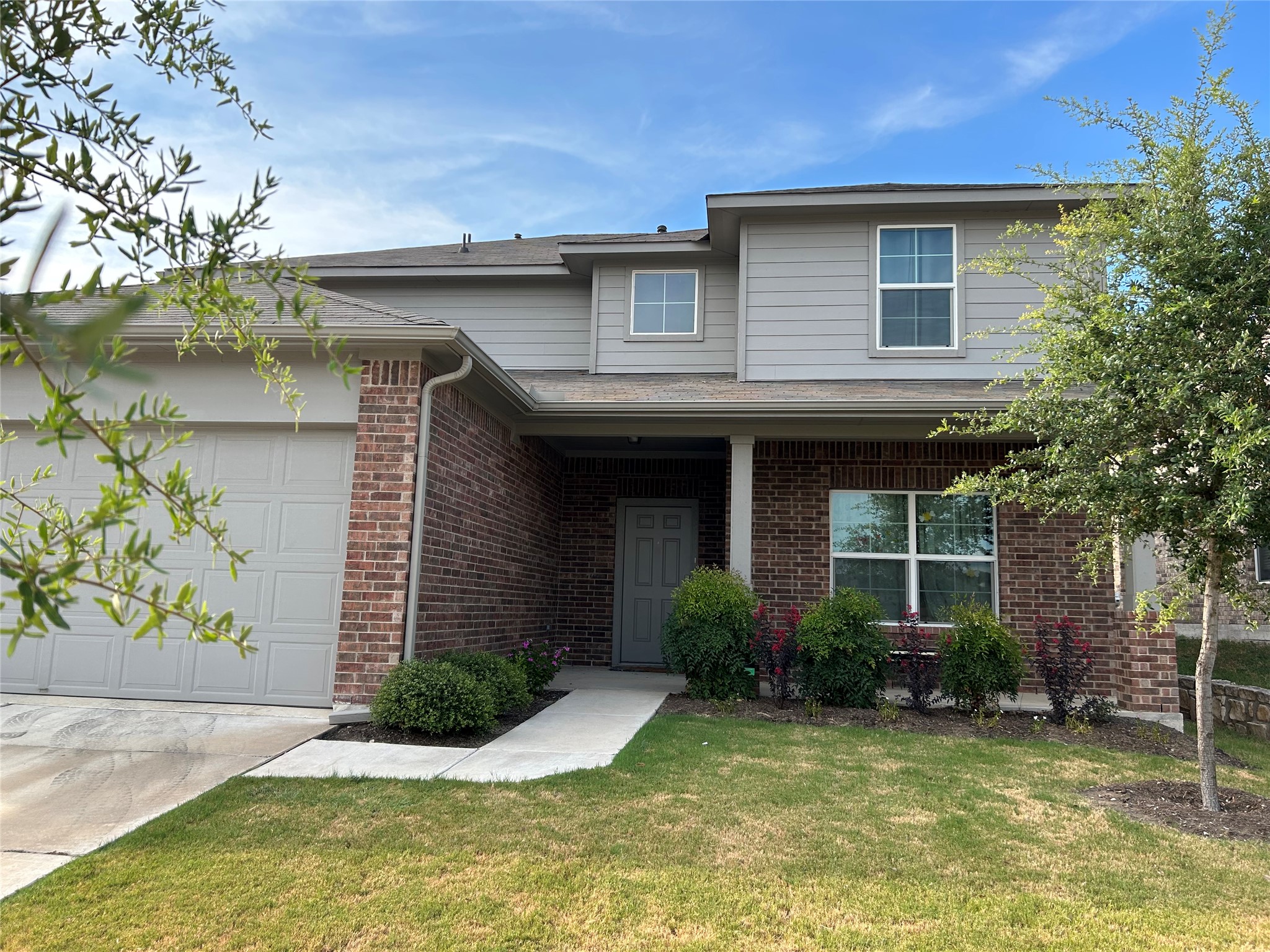 Traditional home featuring brick siding, a front lawn, and an attached garage