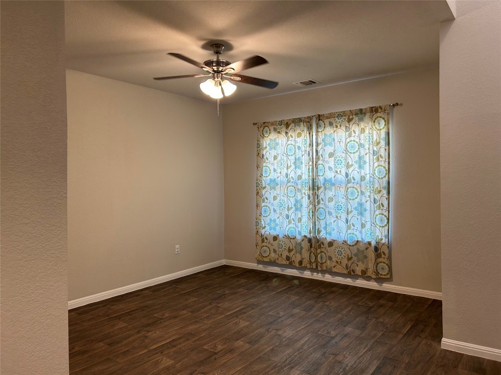 2212 Baugh Road Austin, TX 78754 - Photo 11 of 36 Empty room featuring dark wood-type flooring, ceiling fan, and a textured wall