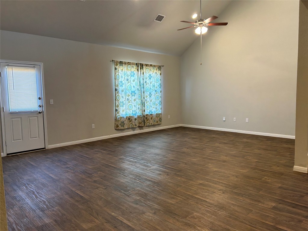 2212 Baugh Road Austin, TX 78754 - Photo 13 of 36 Empty room with dark wood-type flooring, ceiling fan, and high vaulted ceiling