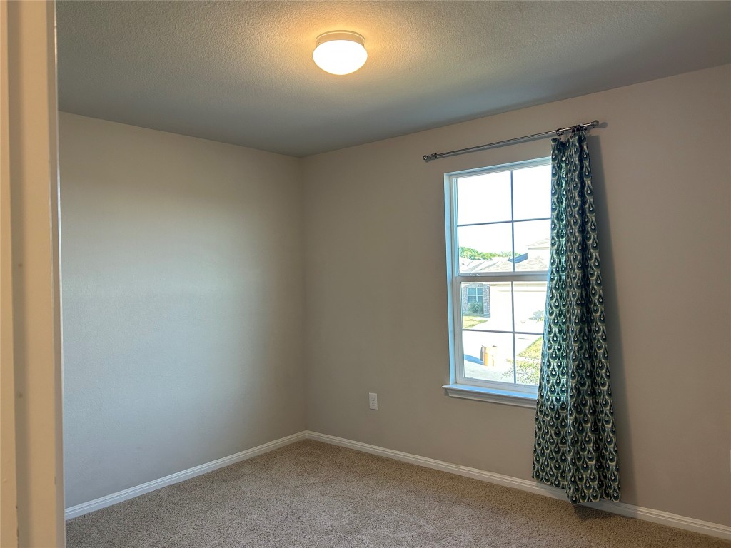 2212 Baugh Road Austin, TX 78754 - Photo 27 of 36 Carpeted empty room featuring a textured ceiling and baseboards