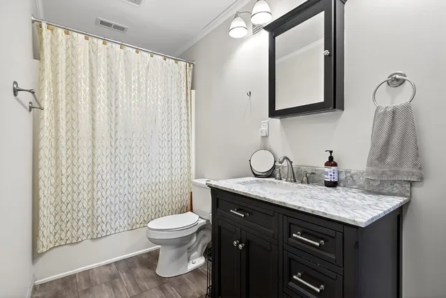 a bathroom with a granite countertop sink toilet and mirror