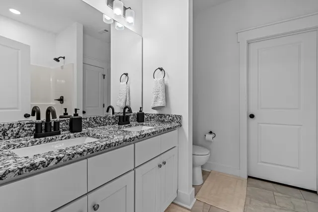 a bathroom with a granite countertop sink a toilet and a mirror