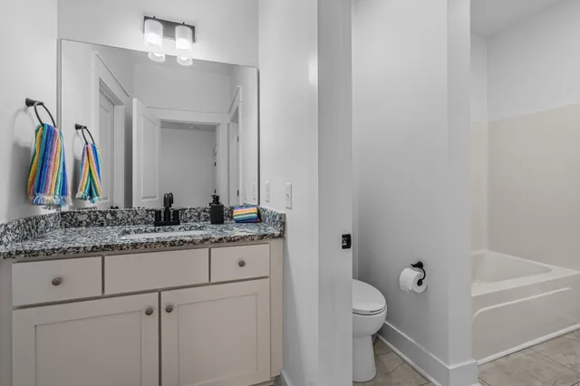 a bathroom with a granite countertop sink a toilet and a mirror