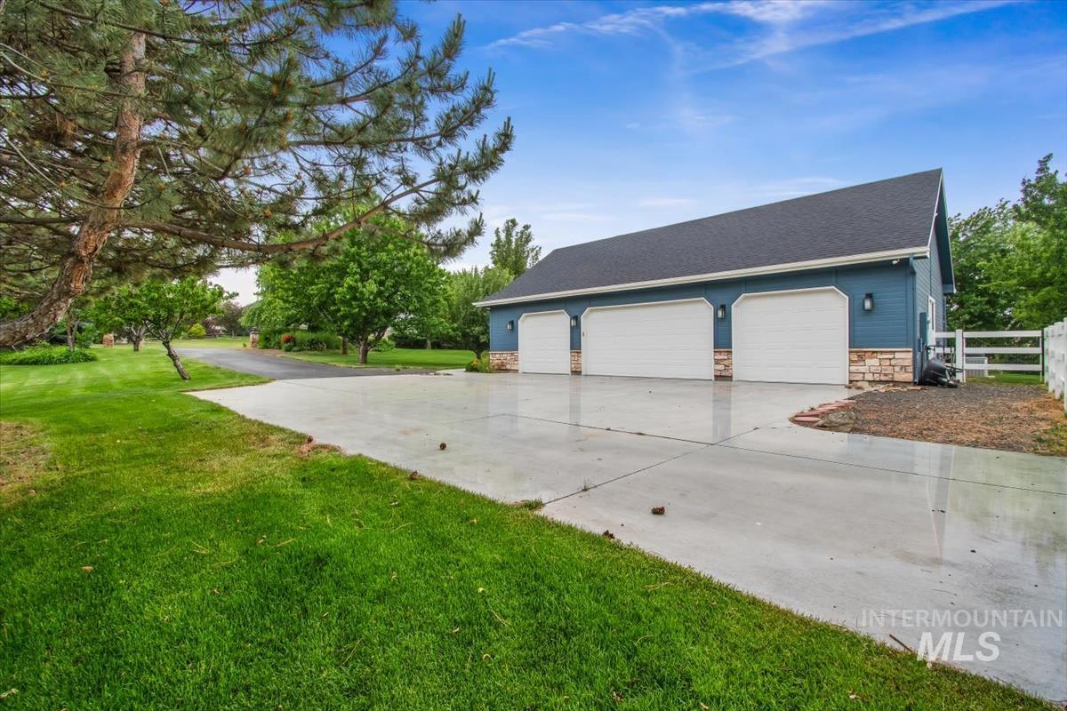 10462 West Lanktree Gulch Road Star, ID 83669 - Photo 41 of 48 Three-car garage with white paneled doors, blue siding, and stone veneer accents