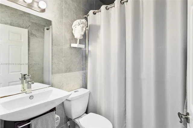 a bathroom with a sink a toilet and shower curtain