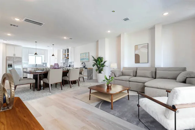 a living room with lots of furniture kitchen view and a dining table