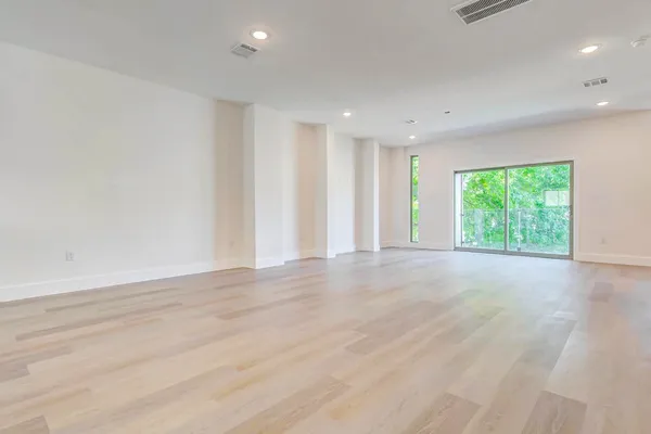 a view of an empty room with wooden floor and a window