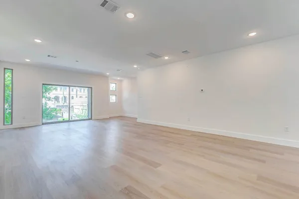 an empty room with wooden floor and windows