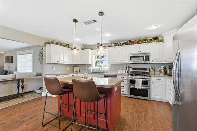 a kitchen with stainless steel appliances a stove a sink refrigerator and a chair