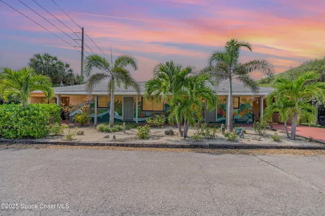 a front view of a house with palm trees