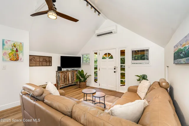 a white kitchen with a refrigerator a stove a sink and a dining table with wooden floor