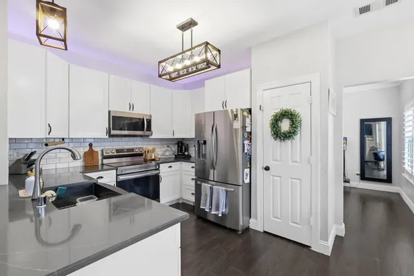a kitchen with stainless steel appliances granite countertop a refrigerator a stove and a sink with chandelier