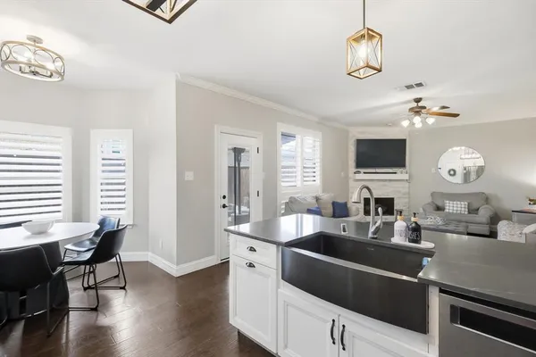 a kitchen with a sink dishwasher a dining table and chairs with wooden floor