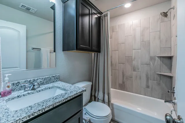 a bathroom with a granite countertop sink toilet and shower