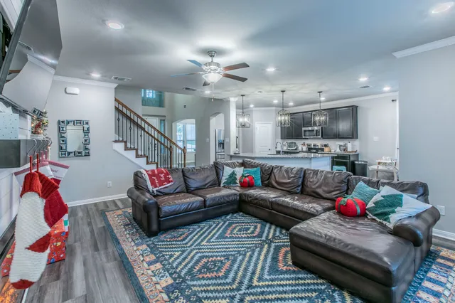 a living room with furniture kitchen view and a chandelier